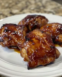 Delicious low carb BBQ chicken thighs on a grill, garnished with herbs