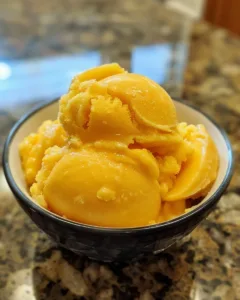 Bowl of perfect peach sorbet garnished with fresh peach slices