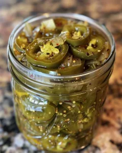 Jar of sweet and spicy hot honey pickled jalapeños on a wooden table