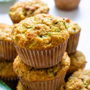 Fluffy Almond Zucchini Muffins served on a plate with fresh zucchini slices.