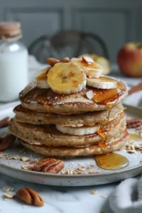 Healthy oatmeal apple pancakes served with syrup and fresh apple slices