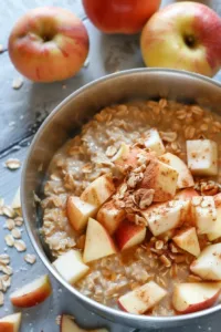One Pot Apple Cinnamon Oatmeal served in a bowl with fresh apples and cinnamon sticks.