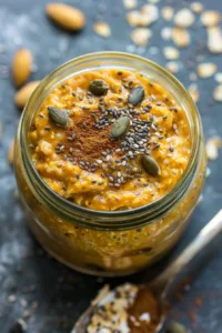 Bowl of pumpkin pie overnight oats with chia seeds topped with pumpkin spice and nuts.