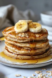 3 ingredient banana oatmeal pancakes stacked on a plate with syrup