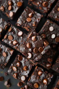 Moist zucchini brownies cut into squares on a wooden plate